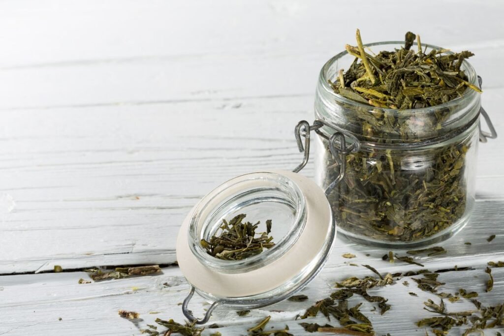 Sencha Tea leaves in a jar on a white wooden background